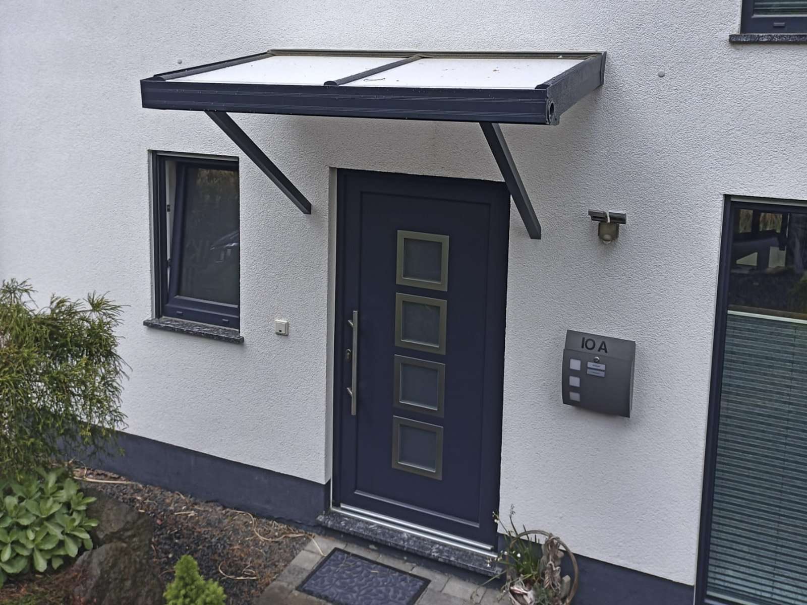 Vordach aus Aluminium mit Glasdach über einem Hauseingang