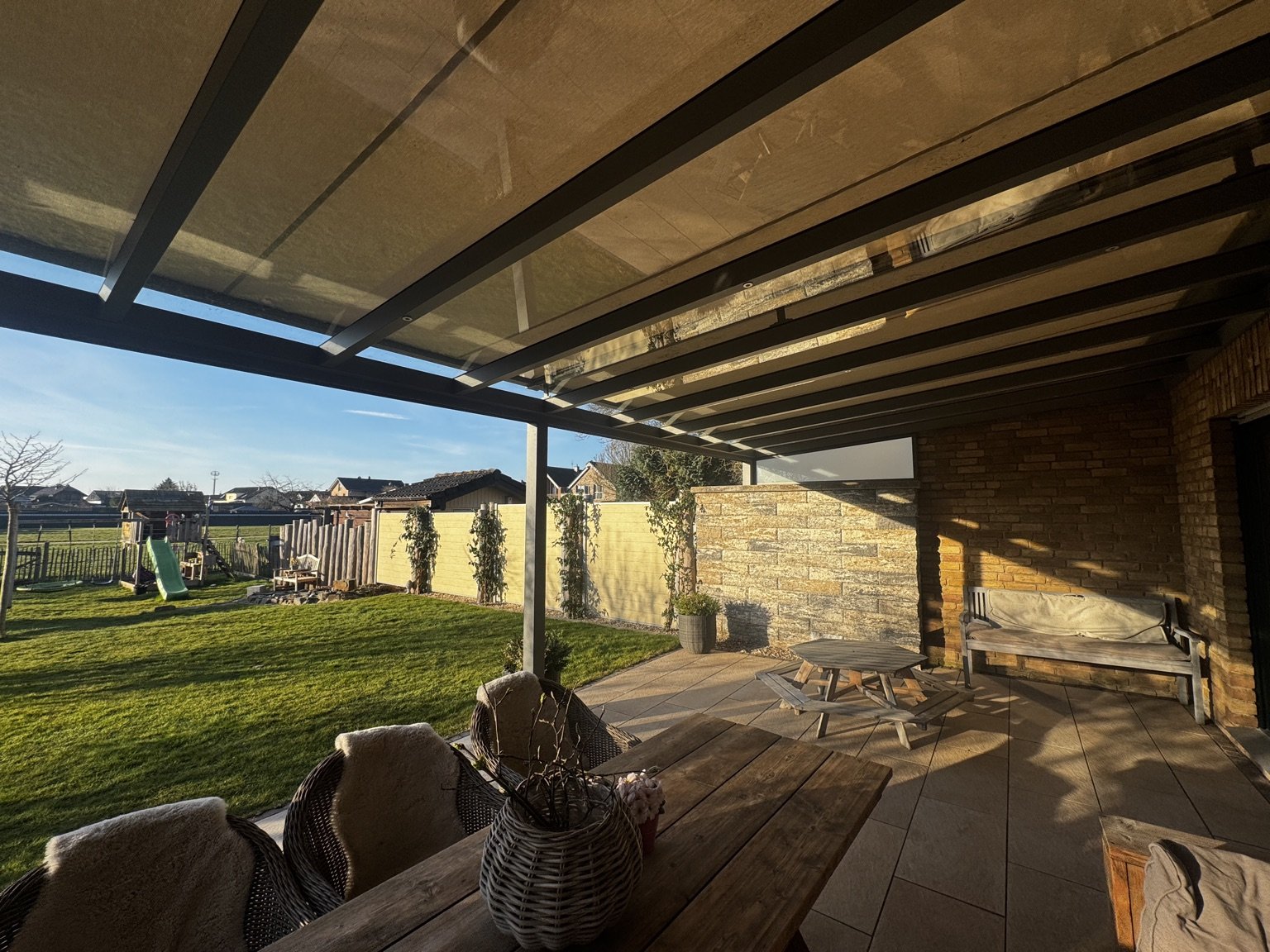 Terrassenüberdachung mit Glasdach über einer Terrasse mit Sitzbereich