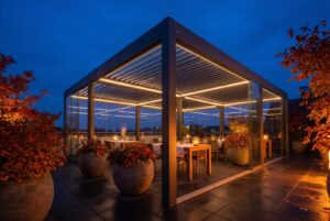 Beleuchteter überdachter Außenbereich eines Restaurants zur blauen Stunde mit gedeckten Tischen