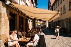 Außengastronomie auf dem öffentlichen Gehweg: Die Markise wirft an einem Sommertag klaren Schatten über die Tische