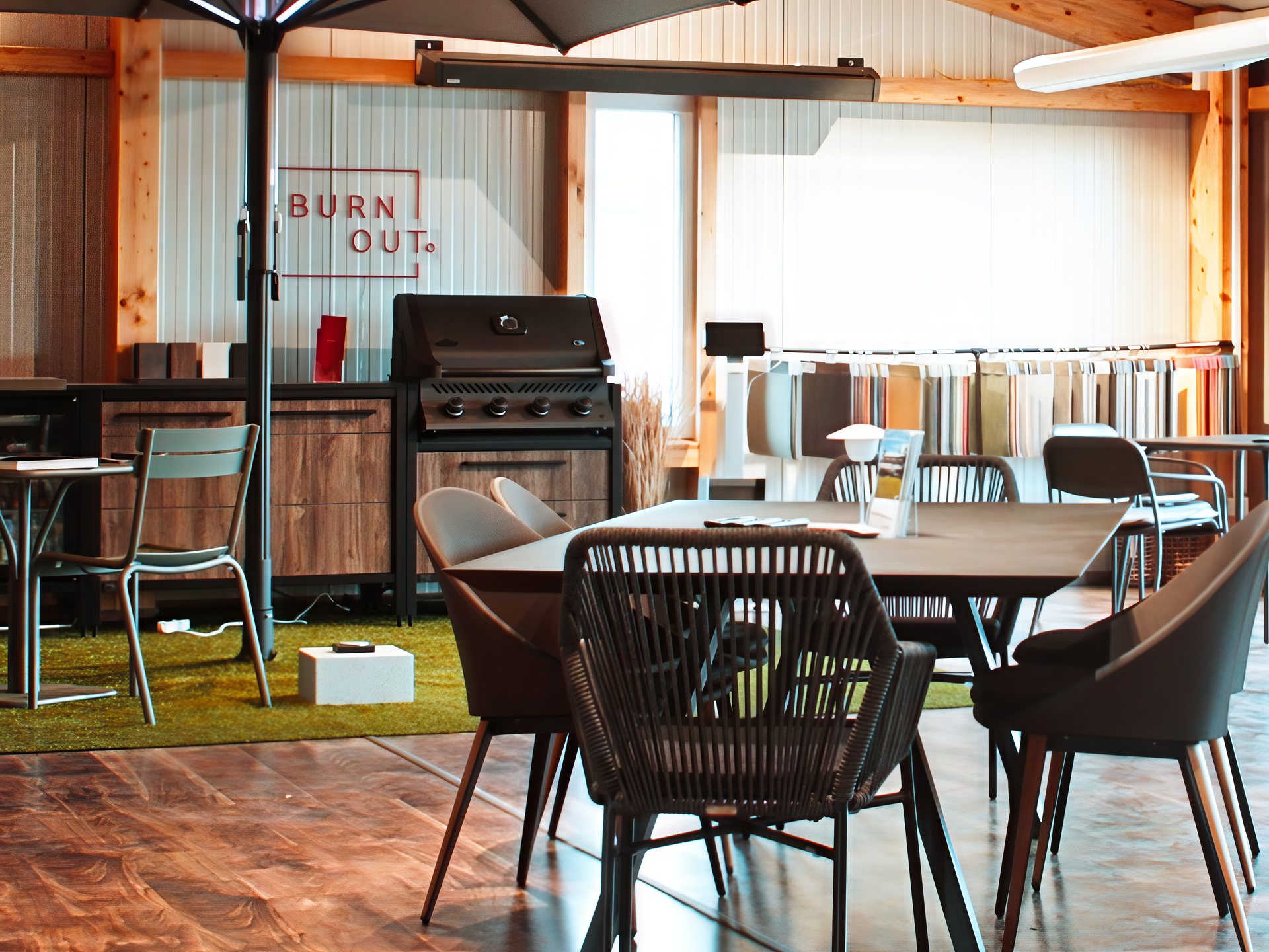 Ausstellungsraum von FT Work & Design mit Esstischgruppen, Sonnenschirm und Outdoor-Küche