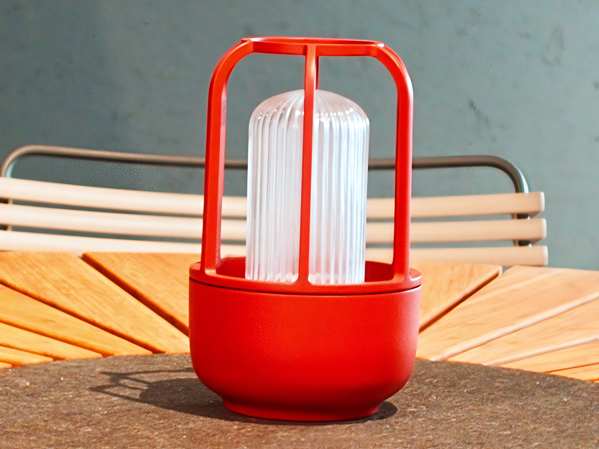 Rote Outdoor-Laterne auf einem runden Holztisch in der Ausstellung von FT Work & Design